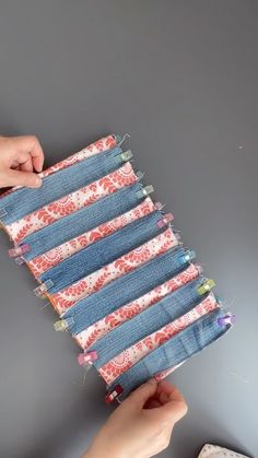 two hands are holding an old pair of jeans that have been sewn together and folded