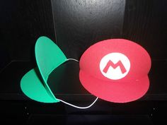 two hats are sitting next to each other in the dark, one is red and one is green