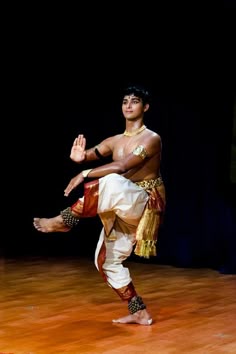 a man in white pants is dancing on a wooden floor