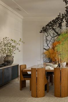 the dining room table is surrounded by wooden chairs and vases with flowers on them