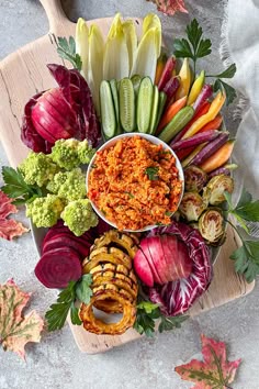 a platter filled with vegetables and sauce on top of a cutting board next to other foods