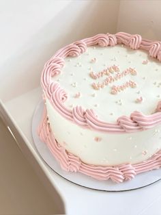 a white cake with pink frosting and the words happy on it is sitting in a box