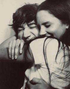 two people are hugging each other in black and white