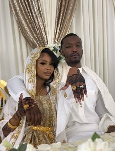 a man and woman sitting next to each other in front of a table with flowers