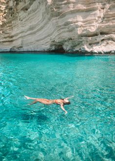 a woman floating in the water near a cliff