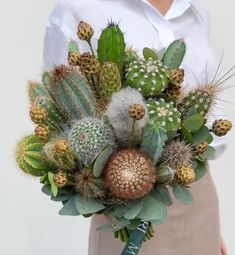 a woman holding a bouquet of cactus and succulents