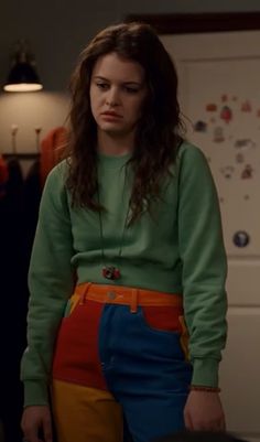 a woman standing in front of a refrigerator wearing an orange, blue and yellow skirt