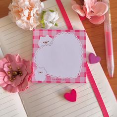 a notepad with a bear on it next to some flowers and a heart shaped pen