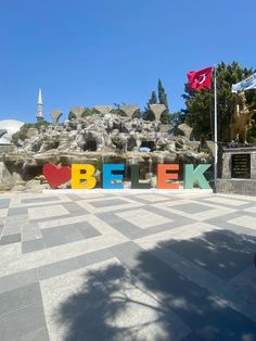 there is a sign that says berk in the middle of a plaza with flags
