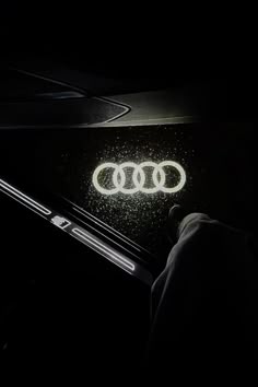 an audi logo is projected on the dashboard of a car at night with headlights shining