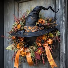 a witch's hat wreath is hanging on a door with orange ribbons and pumpkins