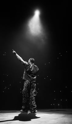 a man standing on top of a stage with his arms in the air and lights behind him