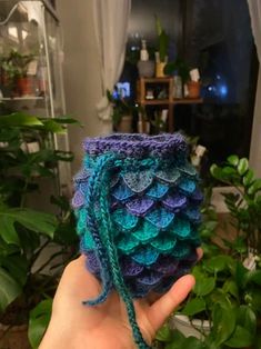 a hand holding a small crocheted pot holder