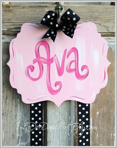a pink sign with black polka dots and a bow hanging from the front of it
