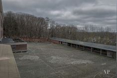 an empty parking lot in front of a building with graffiti on the ground and trees