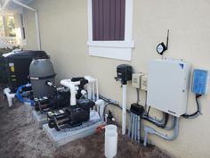 two water heaters are attached to the side of a house with pipes running from them