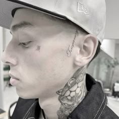a man with a tattoo on his neck wearing a baseball cap and looking off to the side