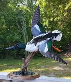a bird statue sitting on top of a wooden table next to a planter filled with flowers