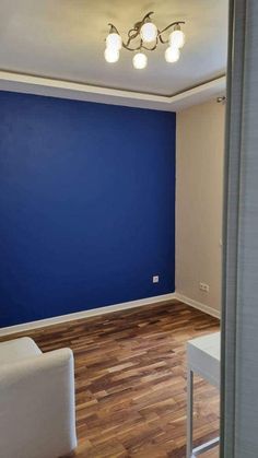 an empty room with blue walls and wooden floors