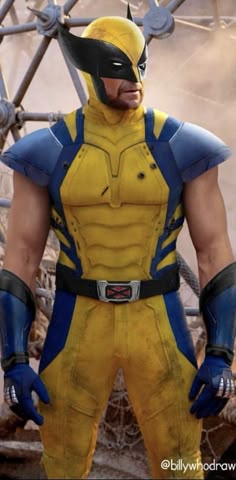 a man in a yellow and blue costume standing with his hands on his hips, looking at the camera