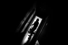 a person standing in the doorway of a dark room with their hand out to someone