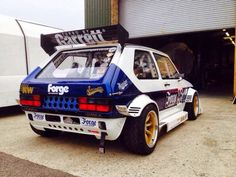 an old race car parked in front of a garage