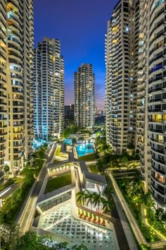 an aerial view of some very tall buildings in the city at night with lights on