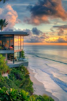 a house on the beach at sunset overlooking the ocean