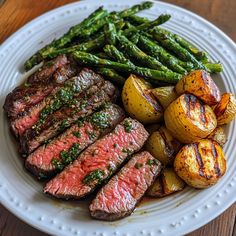 grilled steak, potatoes and asparagus on a white plate with wooden table