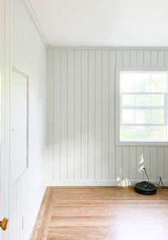 an empty room with hard wood floors and white paint on the walls, along with a window