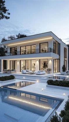 a large white house with lots of windows and lights on the front, along with a swimming pool