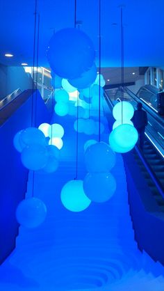 blue lights are hanging from the ceiling above an escalator