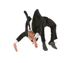 a man in a suit and tie is doing a handstand on the floor