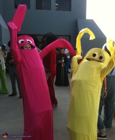 two people dressed in costumes standing next to each other with arms up and hands raised