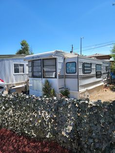 an rv is parked in front of a house with a fence around it and a car behind it