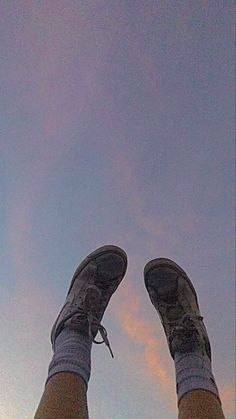 a person with their feet up in the air on a sunny day, wearing blue jeans and sneakers