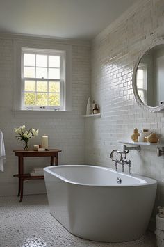 a white bath tub sitting under a bathroom window