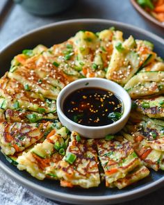 a plate with some food on top of it and sauce in the bowl next to it
