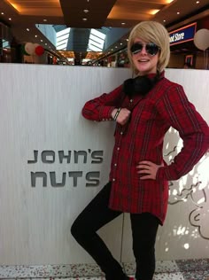 a woman standing in front of a sign with her hands on her hips and wearing sunglasses