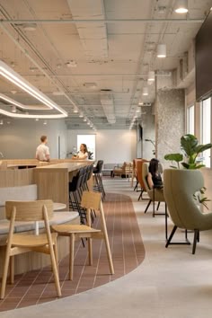 an office with chairs, desks and people sitting at the counter in front of large windows
