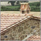 an old stone building with a birdhouse on the roof and trees in the background
