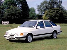 a white car parked on top of a lush green field