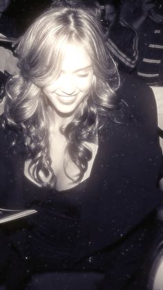 a woman sitting in a chair looking at her cell phone