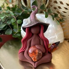 a small figurine with a hat on it sitting on a table next to a potted plant