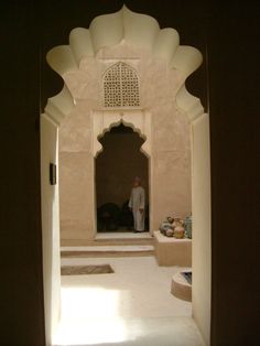 a man standing in the doorway of a building with an archway leading to another room