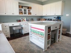 a white kitchen with lots of drawers and shelves on the wall next to an area rug