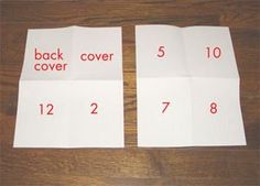 four pieces of white paper with red numbers on them sitting on a wooden table next to each other