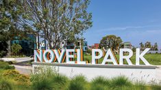 there is a sign that says novel park in front of some trees and grass on the other side