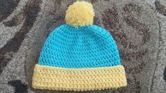 a crocheted blue and yellow hat laying on carpet