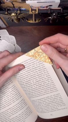 two hands holding an open book on top of a table
